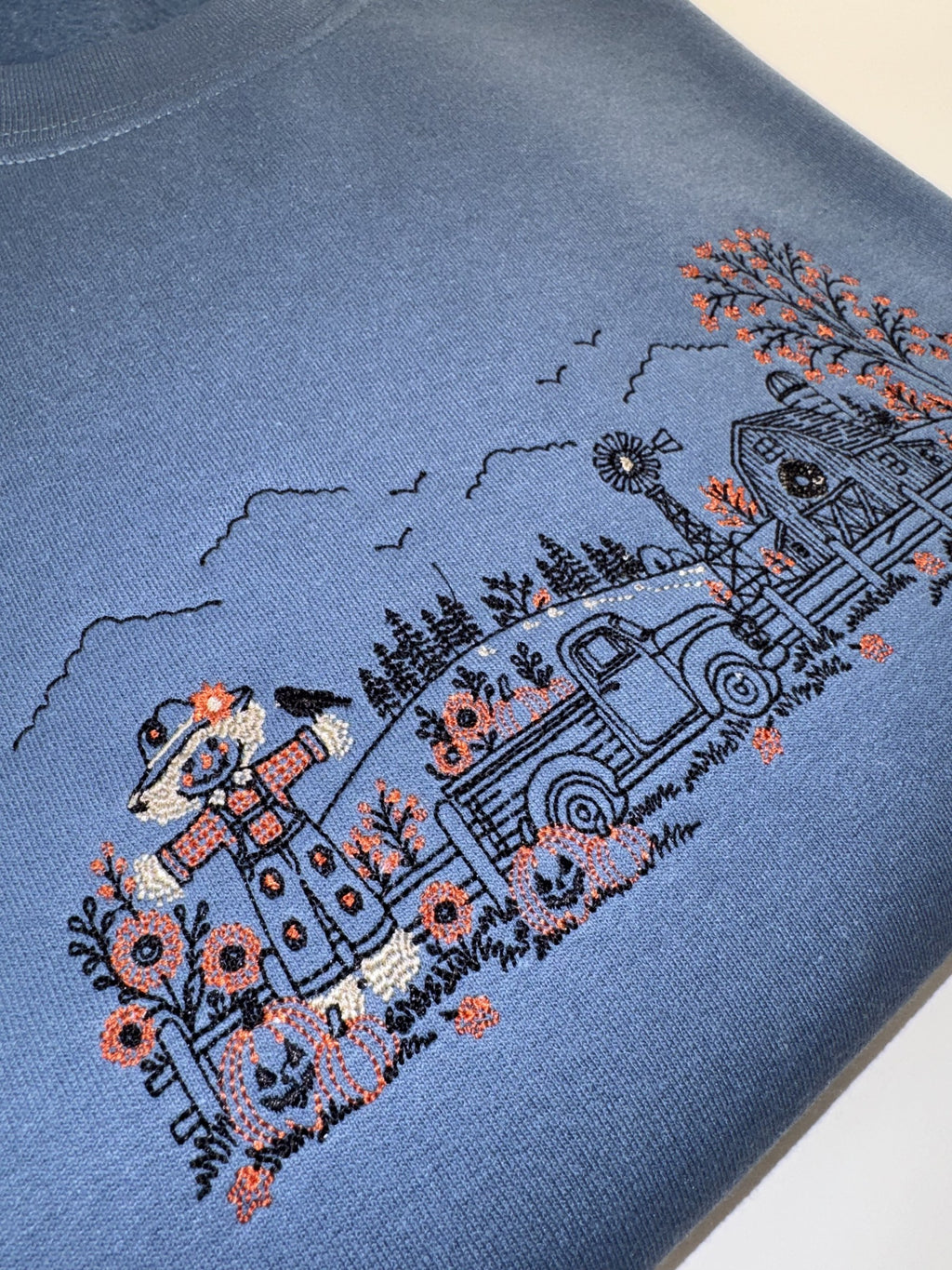 Close up of the scarecrow, jack-o-lanterns and pickup truck on the Indigo Blue Autumn Farm crewneck