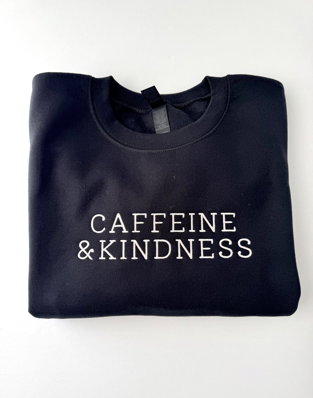 Caffeine & Kindness embroidered in cream thread on a Black crewneck
