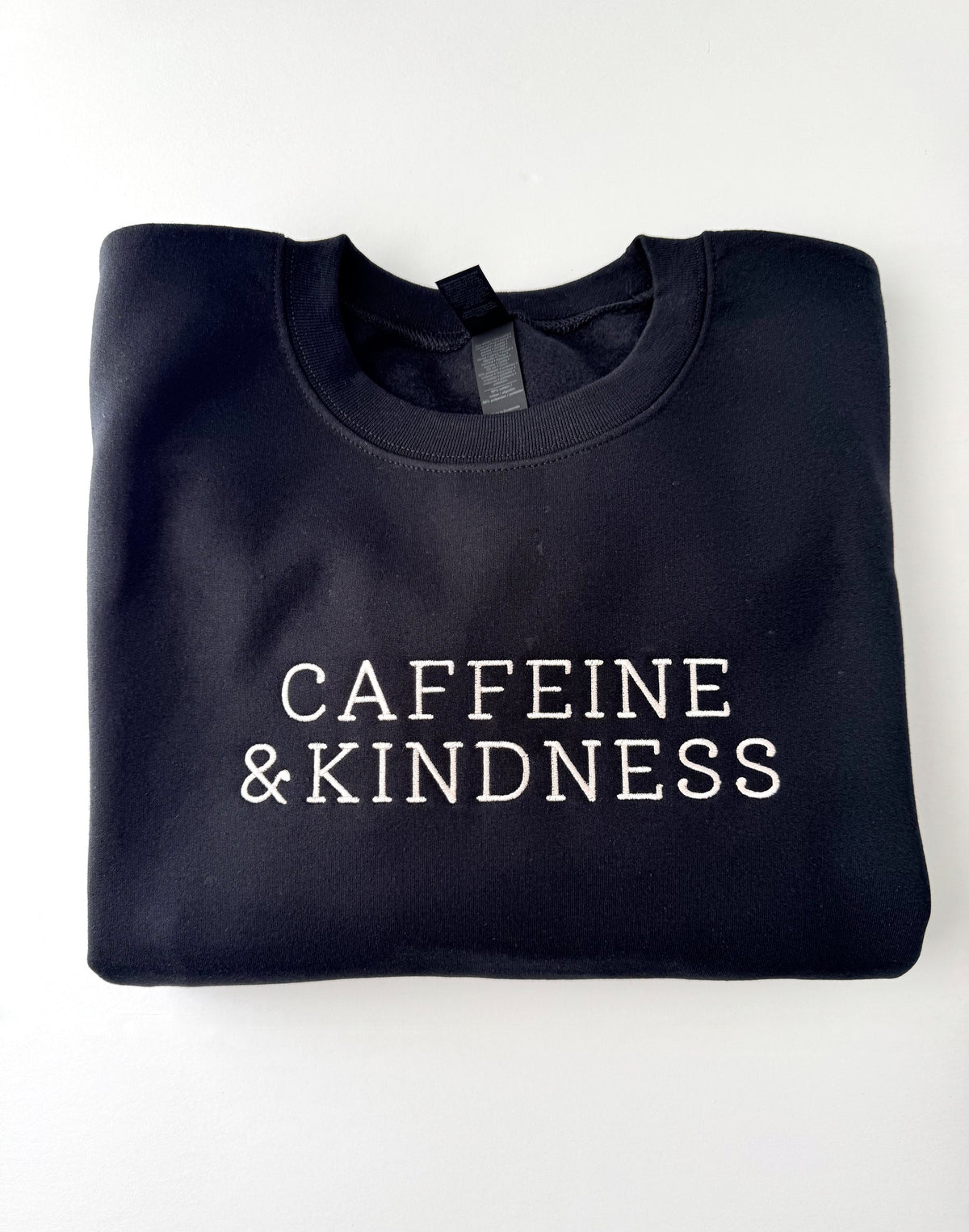 Caffeine & Kindness embroidered in cream thread on a Black crewneck