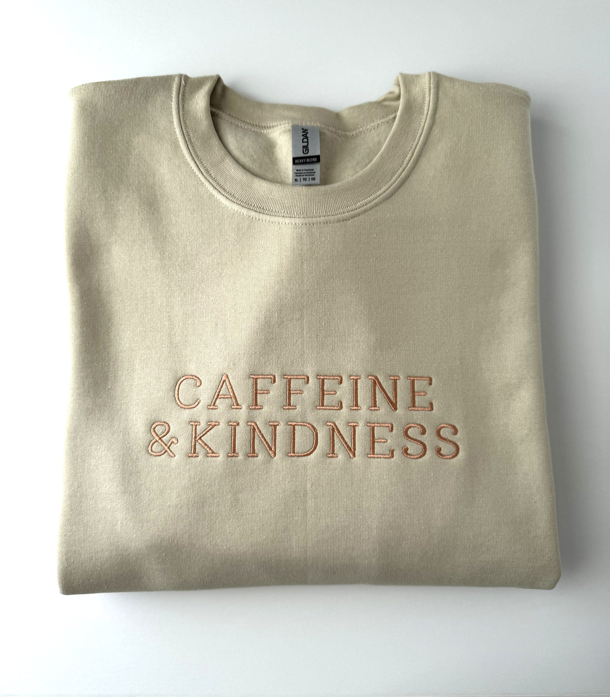 Caffeine & Kindness embroidered in copper thread on a Sand crewneck