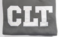 Close up of the white CLT appliqué letters on a Pepper crewneck