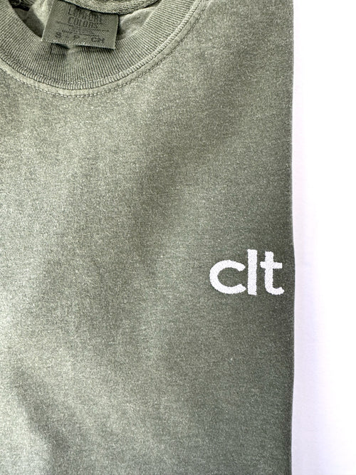 Close up of the white clt embroidery on a Moss tee