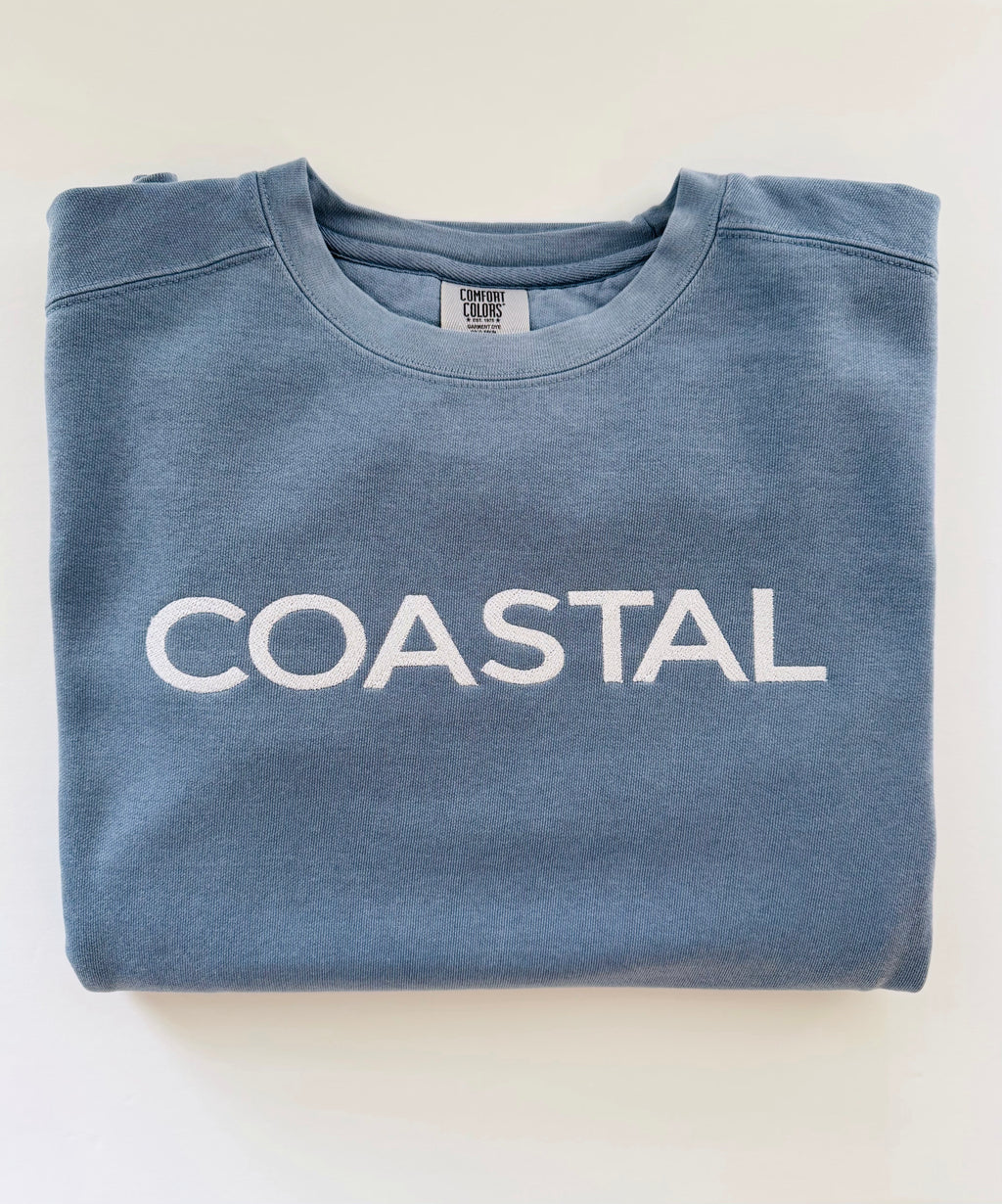 Coastal embroidered crewneck in Blue Jean, folded with the collar showing