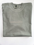 Kindness Wins embroidered in cream thread on a Sage tee