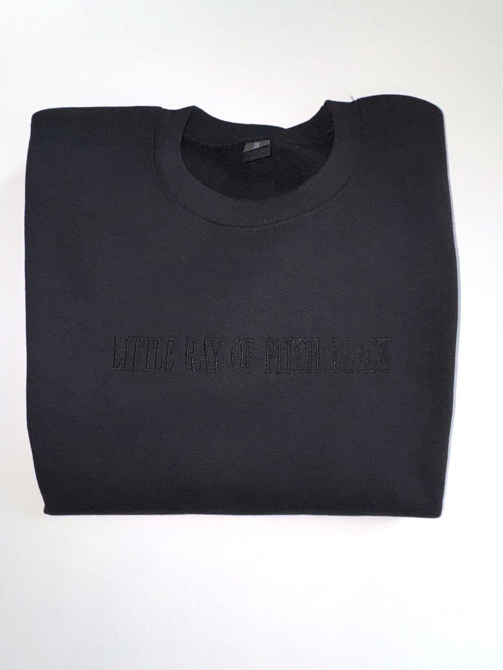 Little Ray of Pitch Black embroidered in black thread on a Black crewneck