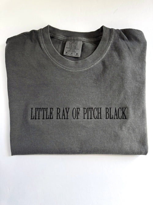 "Little ray of pitch black" embroidered tee in Pepper, folded with the collar showing