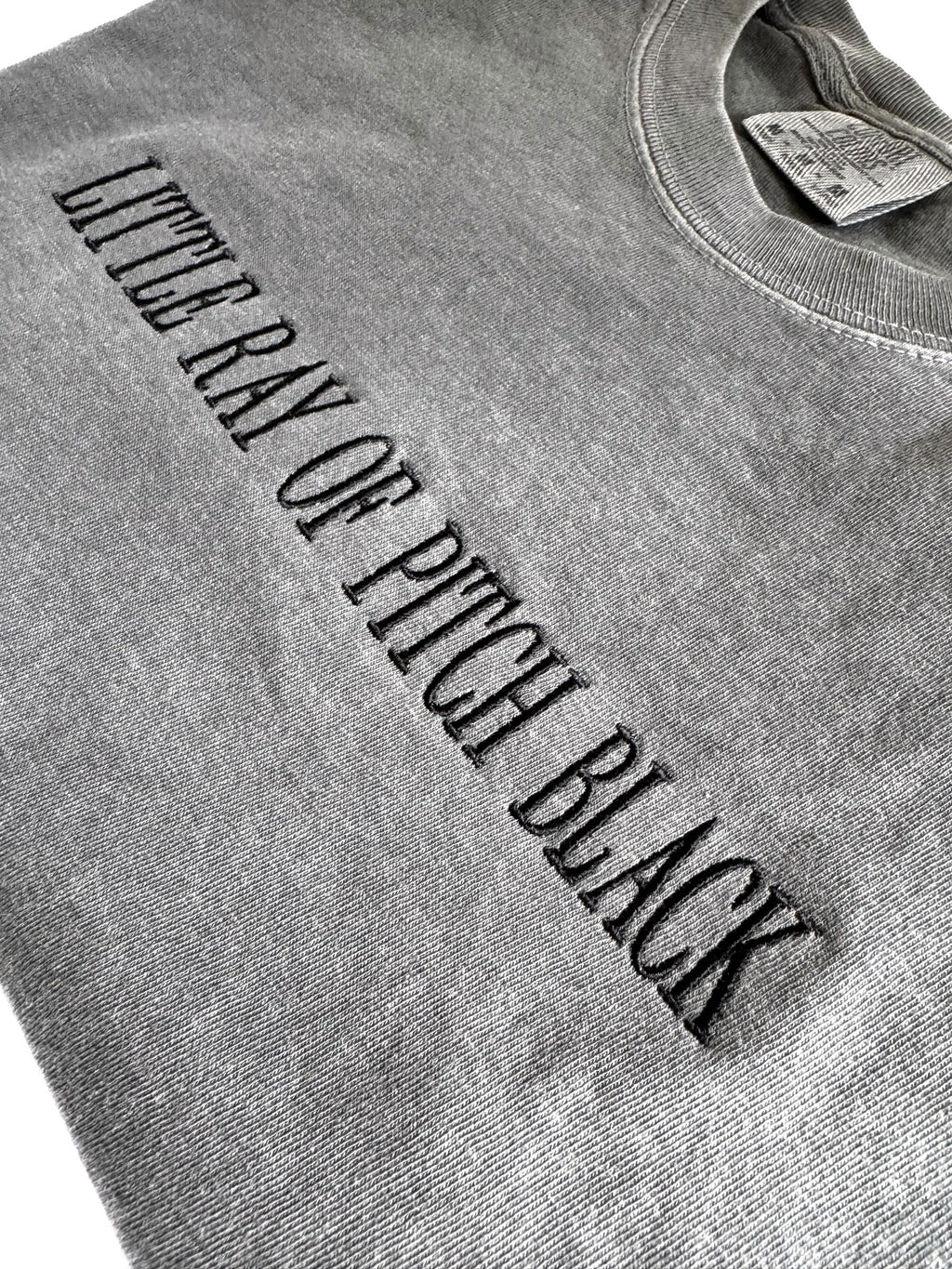 Close-up of the tonal black embroidery on the "Little ray of pitch black" tee in Pepper