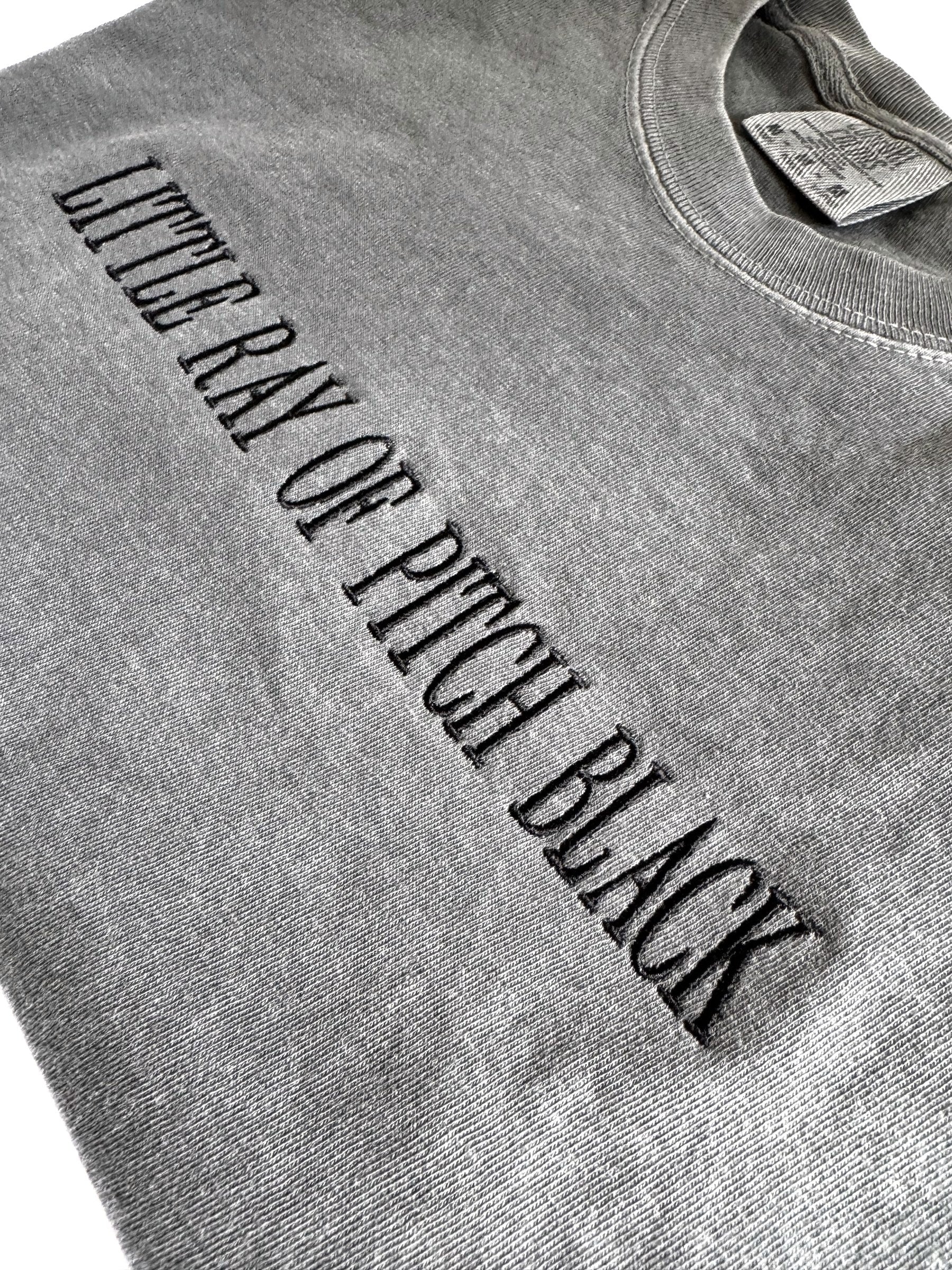Close-up of the tonal black embroidery on the "Little ray of pitch black" tee in Pepper
