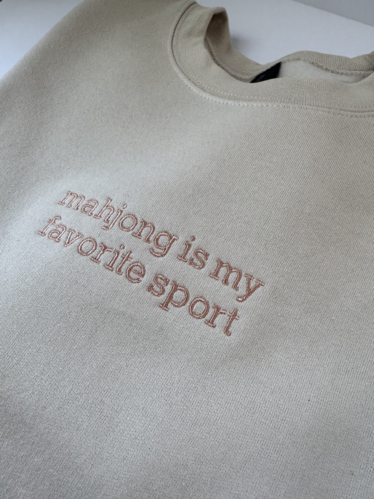 Close up of the Mahjong Is My Favorite Sport embroidery on a Sand crewneck