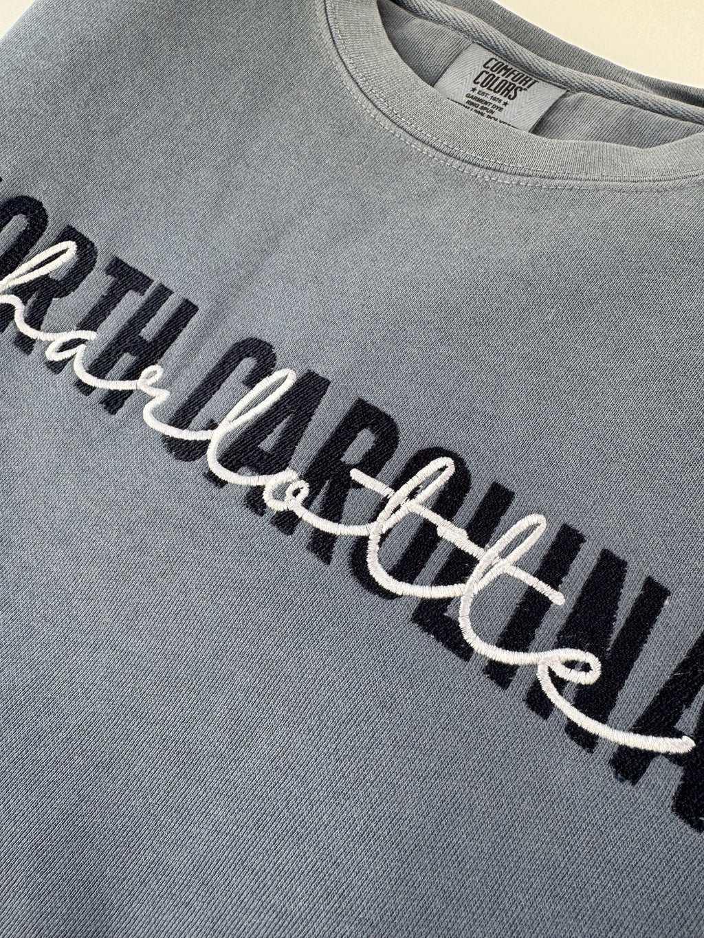 Close up of the North Carolina Charlotte two color embroidery on a Blue Jean crewneck