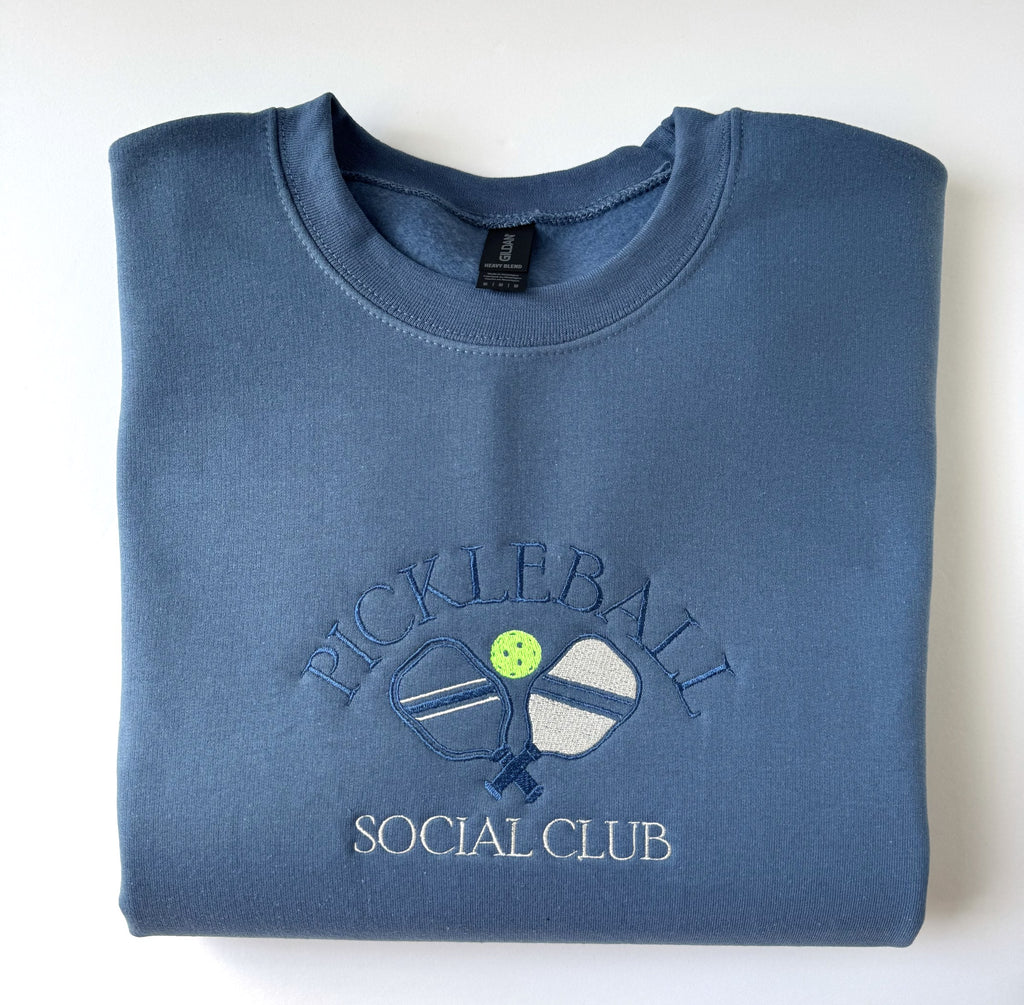 Pickleball Social Club embroidered crewneck in Indigo Blue, folded with the collar showing