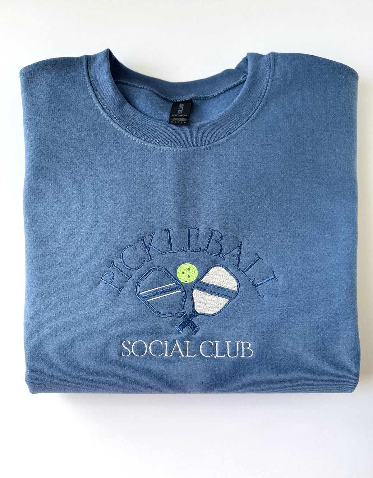 Pickleball Social Club embroidery with crossed paddles on an Indigo Blue crewneck
