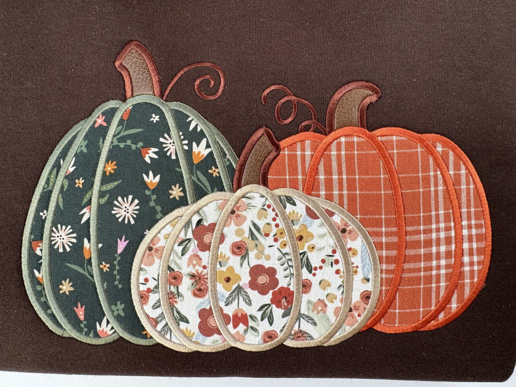 Straight on close up of the three appliquéd pumpkins on the Dark Chocolate Pumpkin Trio crewneck