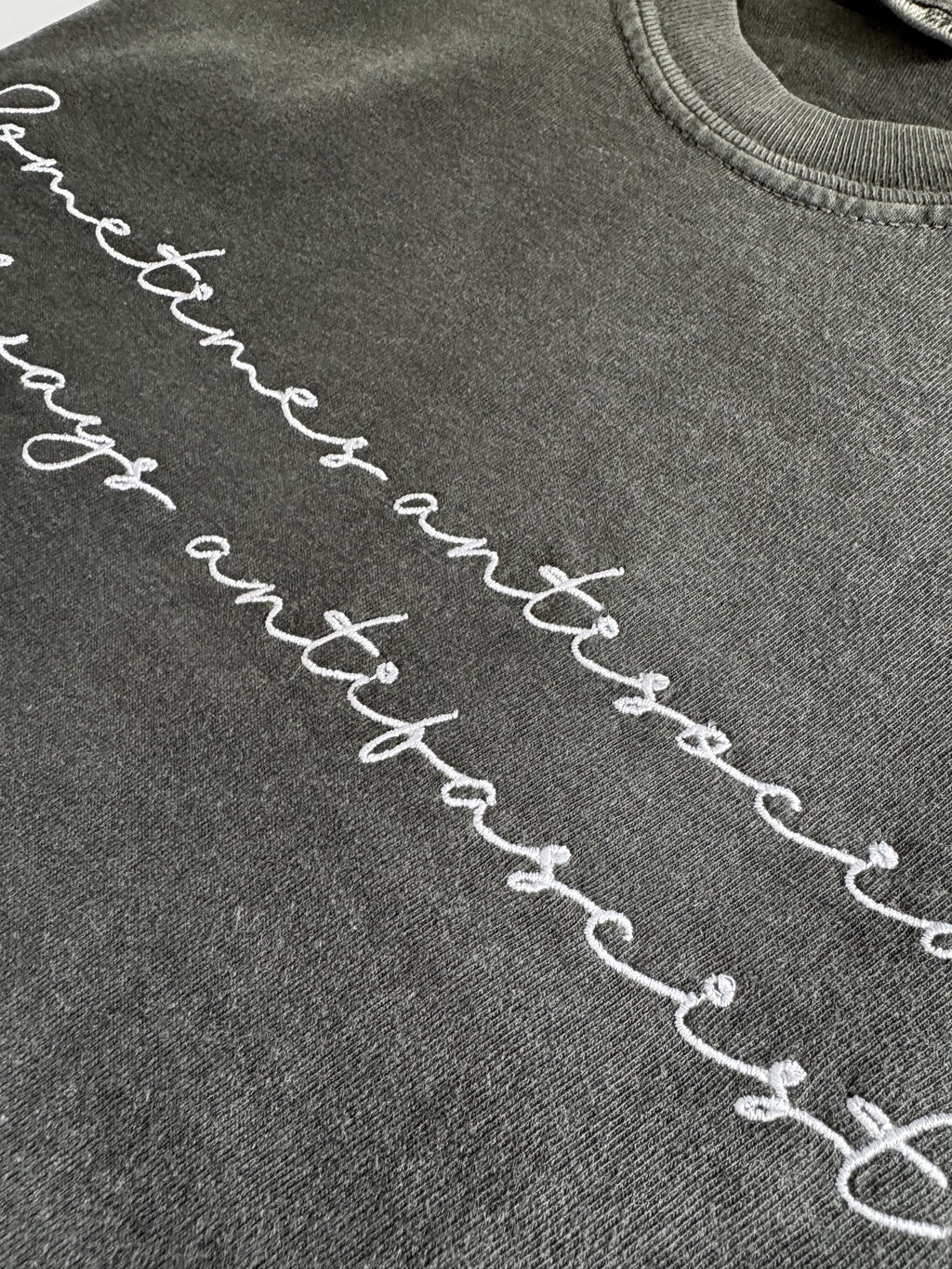 Close-up of the white script embroidery on the "Sometimes antisocial, always antifascist" tee in Pepper