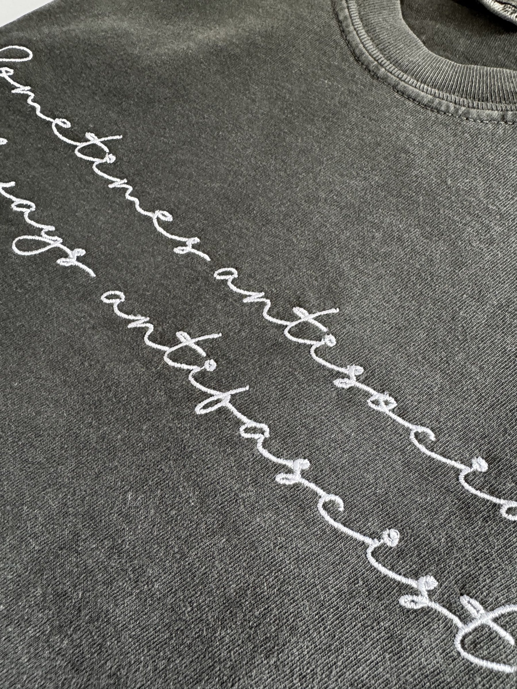 Close-up of the white script embroidery on the "Sometimes antisocial, always antifascist" tee in Pepper