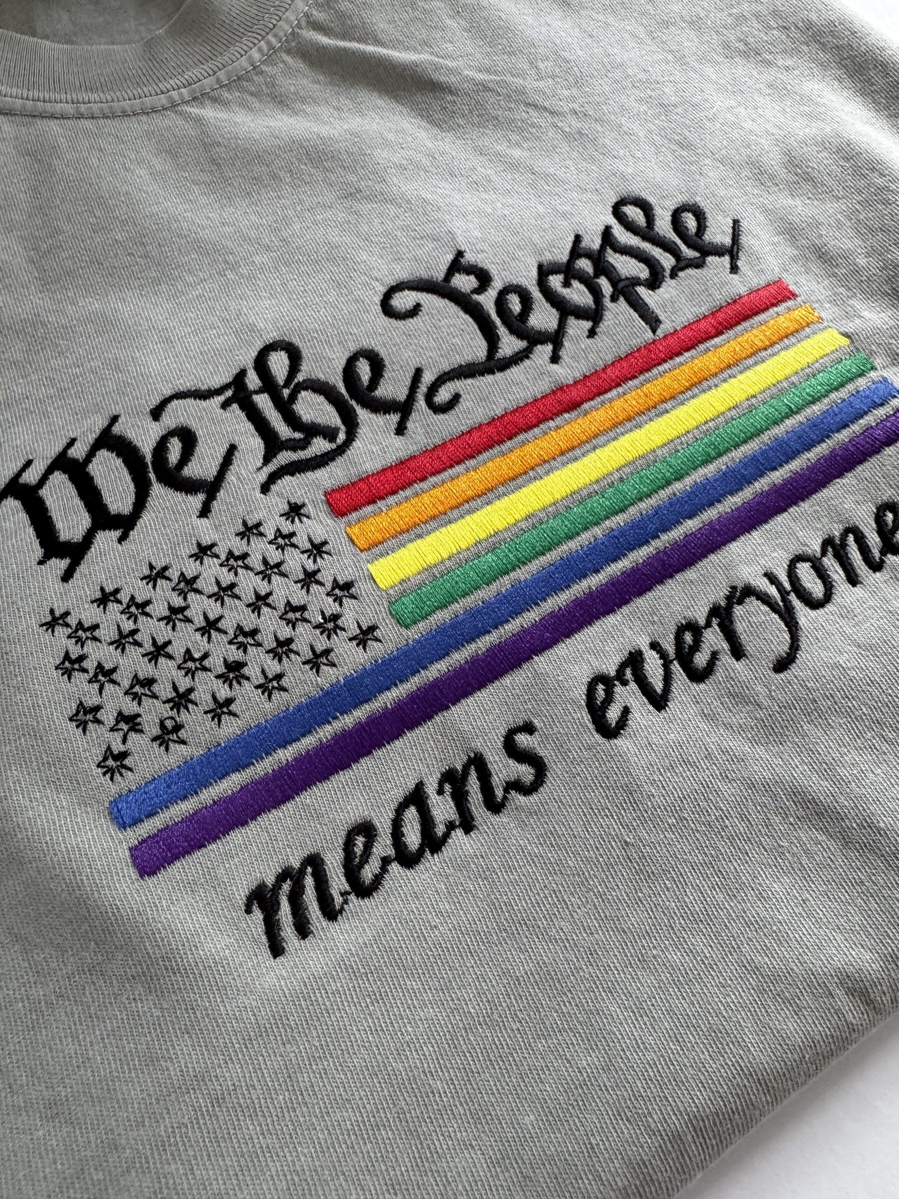 Close-up of the rainbow flag embroidery on the "We The People means everyone" tee